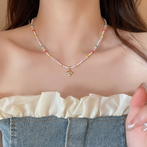 Detail of colorful beaded choker with a golden mushroom pendant on a female model neck