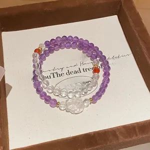 Macro shot of amethyst bead bracelet with white flower charm on vintage jewelry tray