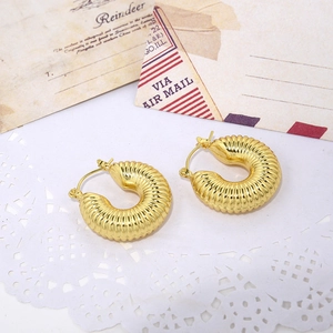 Macro detail of golden twist earrings with textured spiral design on vintage background