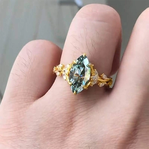 Macro detail of luxury marquise-cut blue gemstone ring with golden vine leaf design