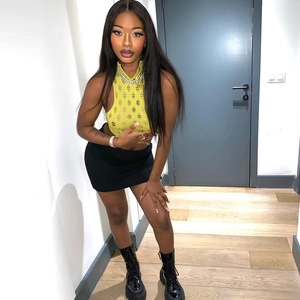 Bright yellow cutout sleeveless crop top paired with a black mini skirt and boots