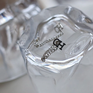 Macro shot of silver C-shaped letter earrings with elegant tassel chain details