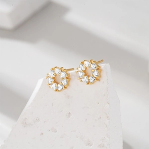 Macro shot of gold hoop earrings featuring crystal heart-shaped zircons on stone