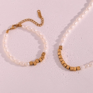 Close-up of freshwater pearl jewelry set with gold cubes on a wet pink surface
