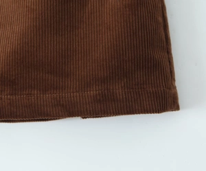 Macro shot of vertical ribbed texture and hem stitching on brown corduroy skirt