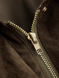 Detailed macro view of high-quality metallic zipper on premium olive suede bomber jacket