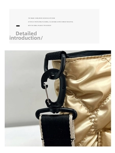 Macro detail of quilted puffer bag with contrast webbing strap and plastic swivel hook
