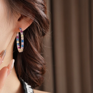 Primo piano di modella con grandi orecchini a cerchio con zirconi colorati sfumati
