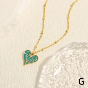 Detail of gold necklace with blue heart pendant on a minimalist ceramic tray