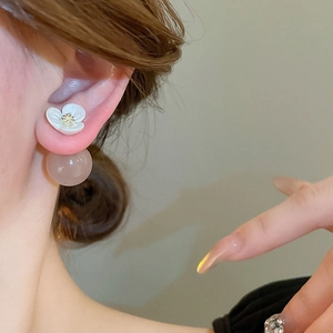 Detail of floral resin earrings with white petals and frosted pink bead on model