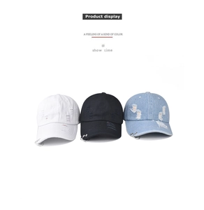 Detailed view of washed denim baseball caps with distressed holes and metal rings decoration