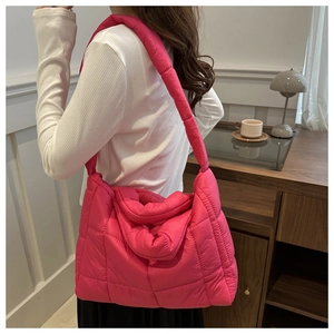 Model wearing a large rose pink quilted puffer cloud bag for a stylish commute look