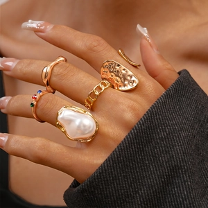 Detailed view of five-piece gold ring set with large pearls and colorful zircons