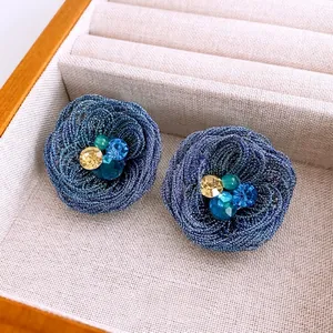 Elegant blue woven flower earrings featuring sparkling crystal center and silver posts