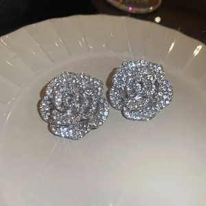 Macro shot of silver flower earrings with sparkling cubic zirconia on a white plate