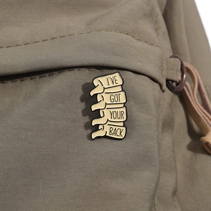 Enamel spine brooch badge with 'I'VE GOT YOUR BACK' text pinned on a canvas bag