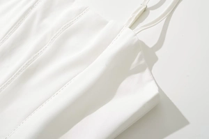 Macro detail of fine vertical seams and delicate thin straps on white camisole dress