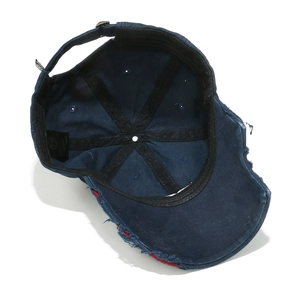Detail showing the inner structure of a distressed navy baseball cap with red piping