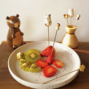 Close-up of cute wooden animal handle fruit forks placed in a fresh strawberry bowl