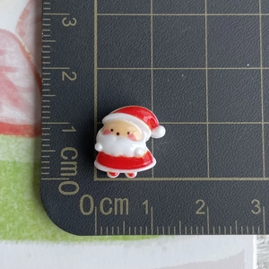 Miniature resin Santa Claus charm shown on a scale mat measuring 1.5cm for DIY crafts