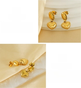 Macro detail of heart-shaped 18K gold-plated stainless steel earrings on silk base