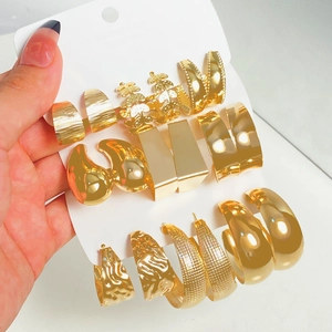 Detailed view of assorted gold geometric earrings and pearls on a white display card