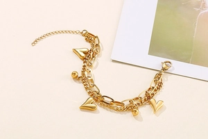 Detail of double-layer gold heart bracelet featuring 3D pendants and adjustable lobster clasp