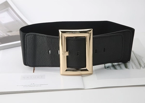 Detail of a wide elastic belt featuring black pebble leather and a large gold square buckle