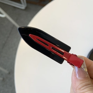 Detailed close-up of glossy black and burgundy red seamless hairpin with metal duckbill clip