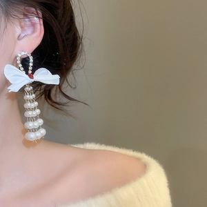 Detailed view of elegant bow pearl drop earrings with sparkling rhinestones and silk texture