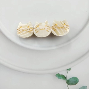 Macro detail of three-head cream acetate cat hair clip with marble texture on white plate