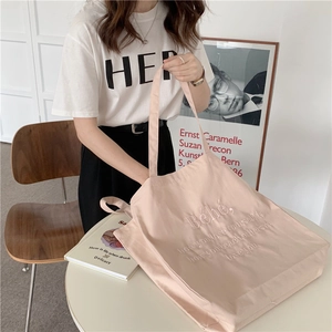 Nahaufnahme der hellrosa Canvas-Tasche mit Bébé-Stickerei auf einem weißen Tisch