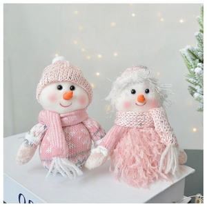 Detail of pink and white plush snowman ornaments with knitted textures in a cozy home setting