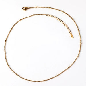 Macro shot of gold stainless steel beaded chain with lobster clasp and S.STEEL tag