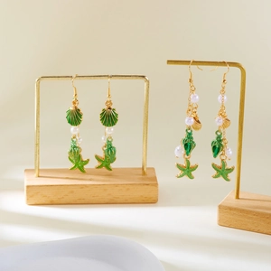 Detailed shot of gold earrings with green starfish and shell charms on display