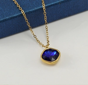 Close-up of gold necklace with a square blue zircon pendant on a luxury gift box