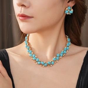 Gros plan sur un ensemble bijoux vintage fleur en or avec pierres turquoises et zircons