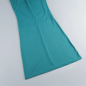 Detail of teal knit maxi dress fabric texture and pleated hemline on flat lay surface