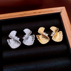 Detail of twisted fan leaf earrings in gold and silver finish with zircon inlay