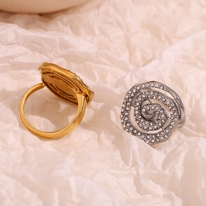 Close-up of gold and silver swirl rings with sparkling rhinestones on textured paper