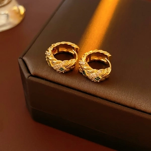 Close-up of vintage gold earrings with green gemstones and white zircons on leather