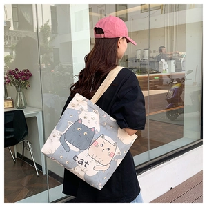 Close-up of a large canvas tote bag with cartoon cat print carried by a model
