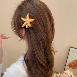 Détail de la pince à cheveux étoile de mer orange brodée avec cristal sur cheveux