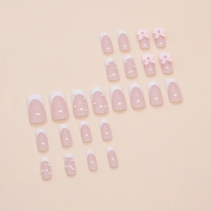 Detail of pink French manicured press-on nails featuring 3D bows and small pearl accents