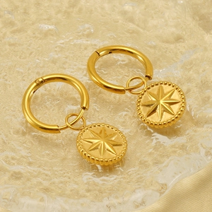 Nahaufnahme von goldenen Edelstahl-Ohrringen mit Türkis und graviertem Stern-Anhänger