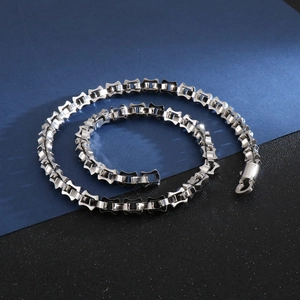 Macro shot of silver geometric link chain necklace with lobster clasp on a dark background