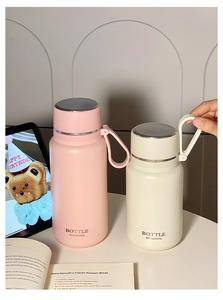 Pink and cream matte insulated tumblers with portable handles on a modern lifestyle desk