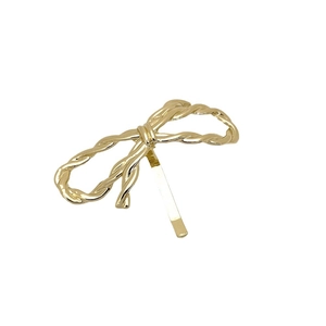 Elegant golden metallic bow hair clip for ponytail styling on a white background