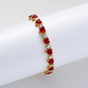Golden tennis bracelet featuring red heart-shaped stones and white round cubic zirconia