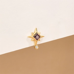 Macro shot of gold starburst ear stud with purple gemstone and clear crystal detail